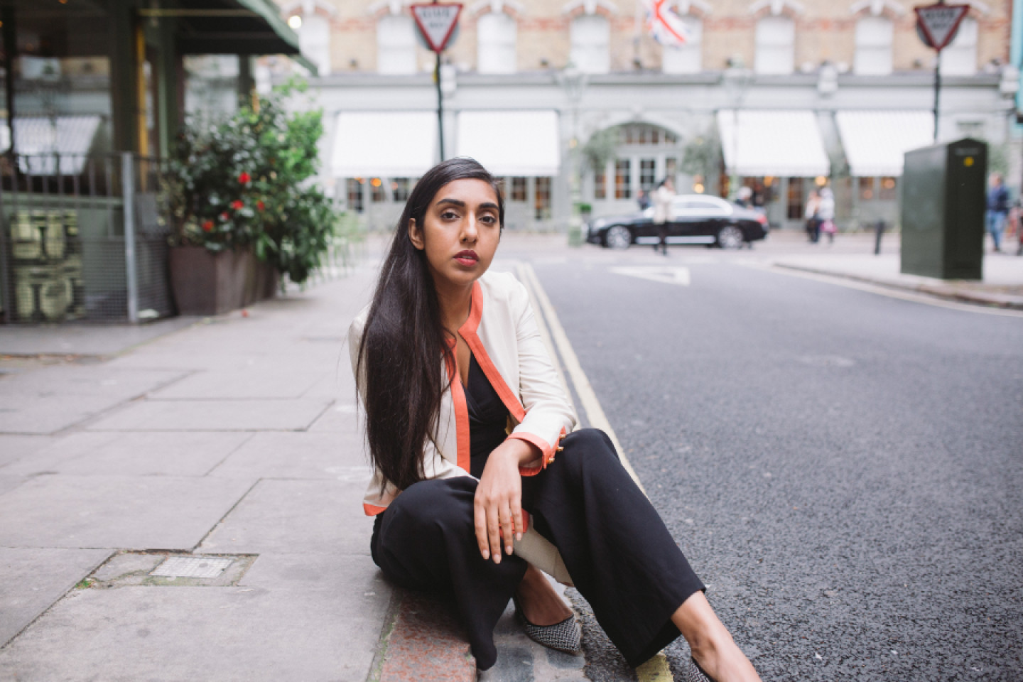 Foto de Rupi Kaur sentada na calçada